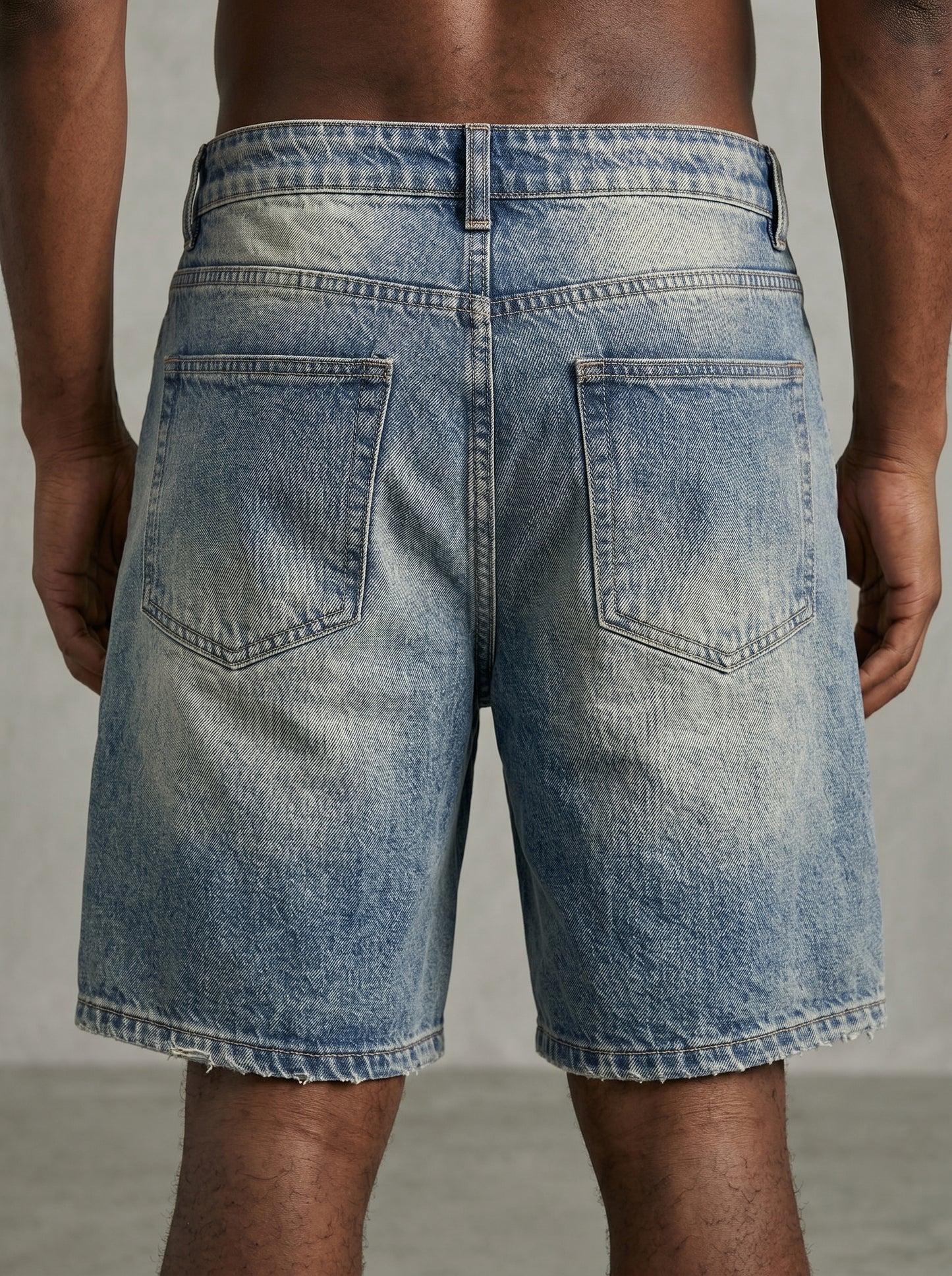 Back view of a person wearing light blue denim shorts on a neutral background