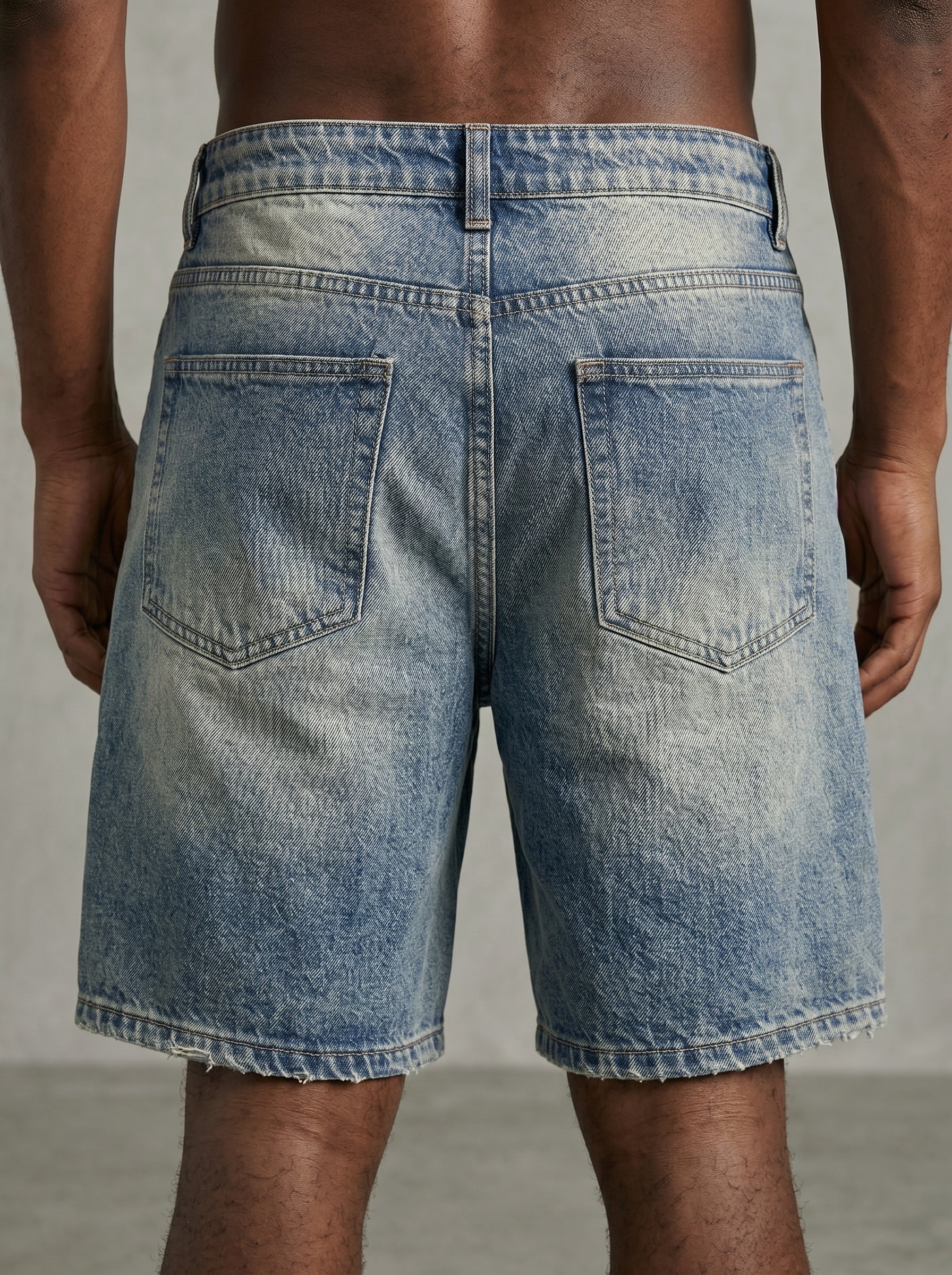 Back view of a person wearing light blue denim shorts on a neutral background